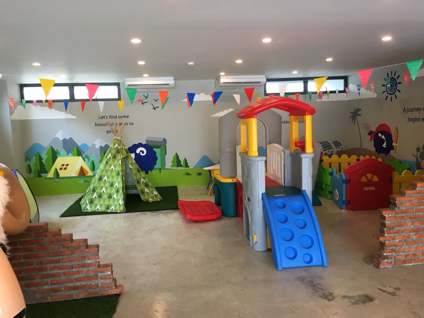 Wide view of kids zone with playhouse, teepee, and pirate mural